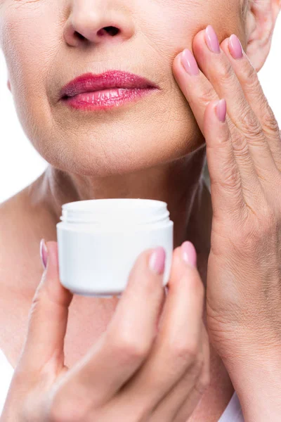 Femme âgée appliquant crème pour le visage — Photo de stock