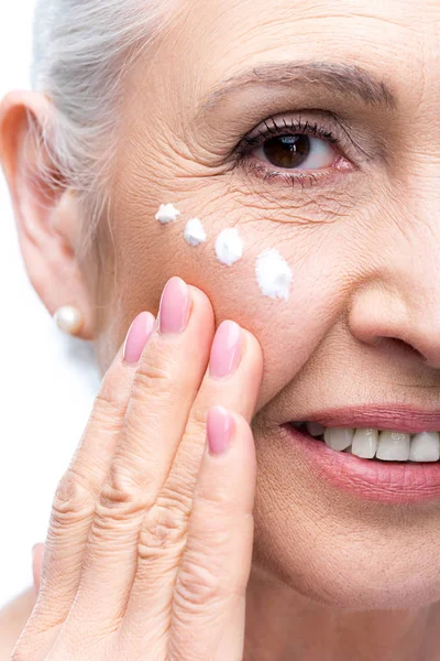 Seniorin trägt Gesichtscreme auf — Stockfoto