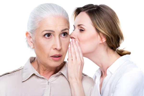 Adult daughter whispering to senior mother — Stock Photo