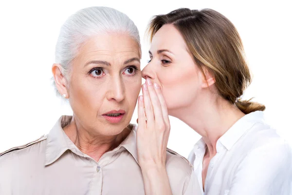 Hija adulta susurrando a la madre mayor - foto de stock