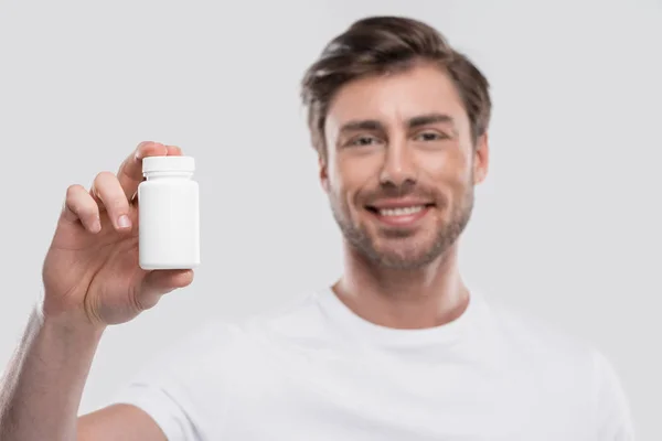 Homme présentant des vitamines en bouteille — Photo de stock