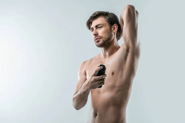 Мужчина без рубашки, распыляющий дезодорант — стоковое фото