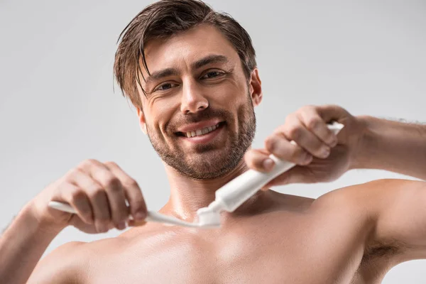 Hombre sonriente con cepillo de dientes y pasta de dientes - foto de stock