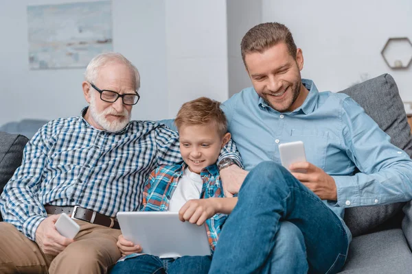 Family sitting on couch with devices — Stock Photo