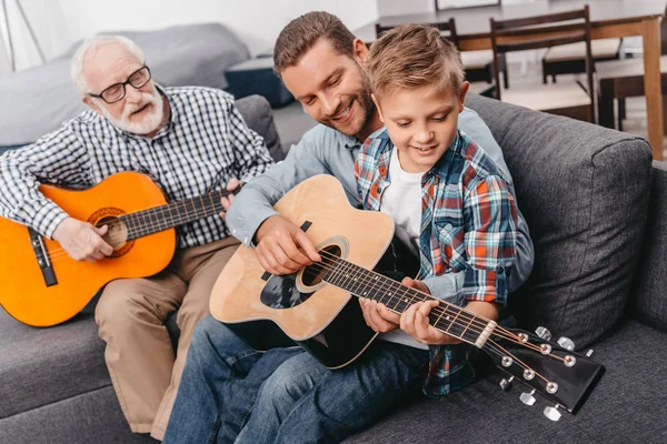 Padre ayudando a hijo a tocar la guitarra - foto de stock