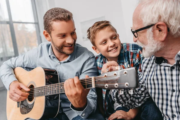Мужчина играет на гитаре с семьей дома — стоковое фото