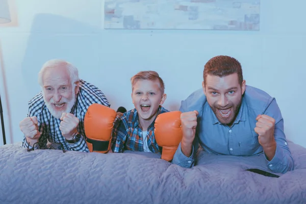 Семья смотрит бокс матч на кровати — стоковое фото