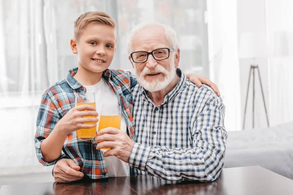 Menino e avô segurando suco de laranja — Fotografia de Stock