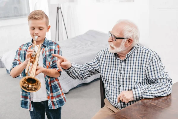 Мальчик репетирует трубу с дедушкой — стоковое фото