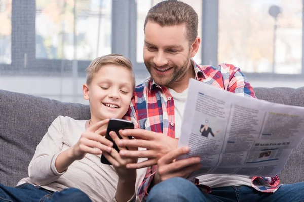 Padre e hijo con periódico y smartphone - foto de stock