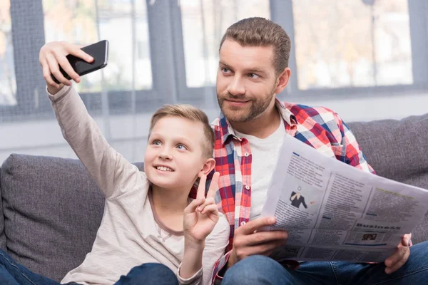 Pai e filho com jornal e smartphone — Fotografia de Stock