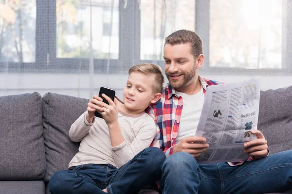 Pai e filho com jornal e smartphone — Fotografia de Stock