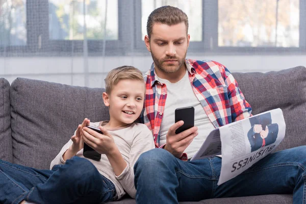 Padre e hijo usando teléfonos inteligentes - foto de stock