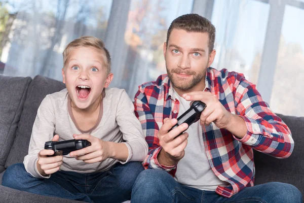 Padre e hijo jugando con joysticks - foto de stock