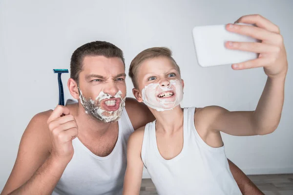 Padre e hijo afeitándose juntos - foto de stock