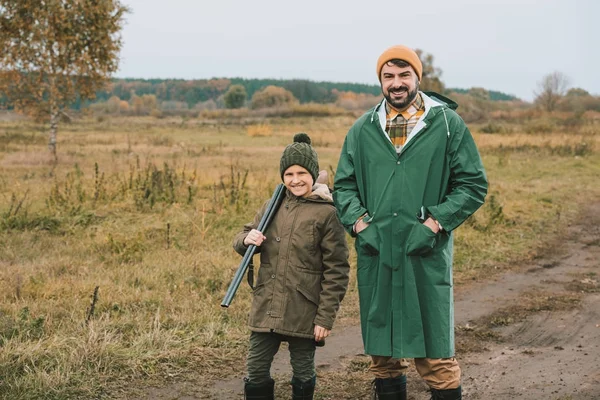 Padre e hijo con arma posando ante la cámara - foto de stock