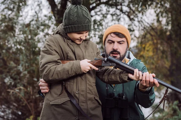 Padre mostrando hijo cómo cargar arma - foto de stock