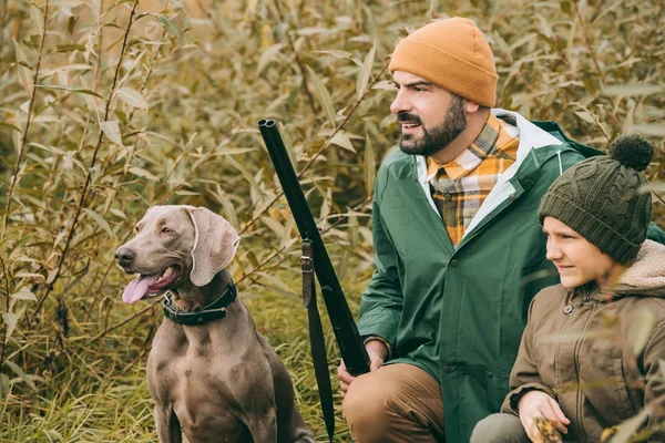 Père et fils accroupis dans les buissons à la chasse — Photo de stock