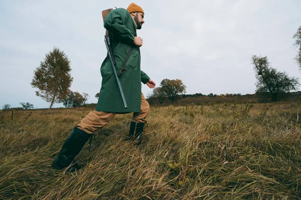 Hunter going with gun in field — Stock Photo