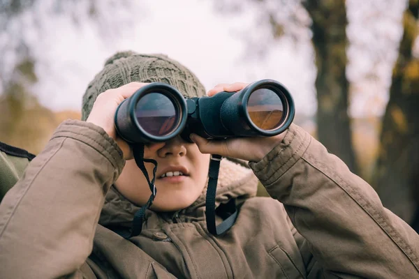 Kid looking through binoculars on nature — Stock Photo