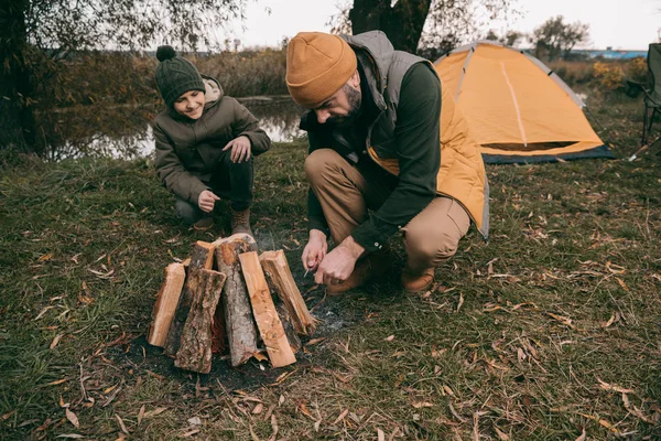 Hijo y padre haciendo hoguera - foto de stock