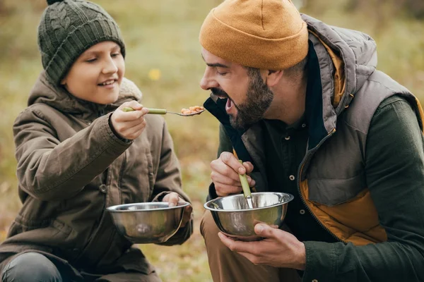 Son giving spoon with beans to father — Stock Photo