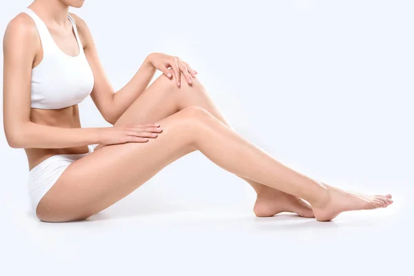 Mujer aplicando crema a las piernas - foto de stock
