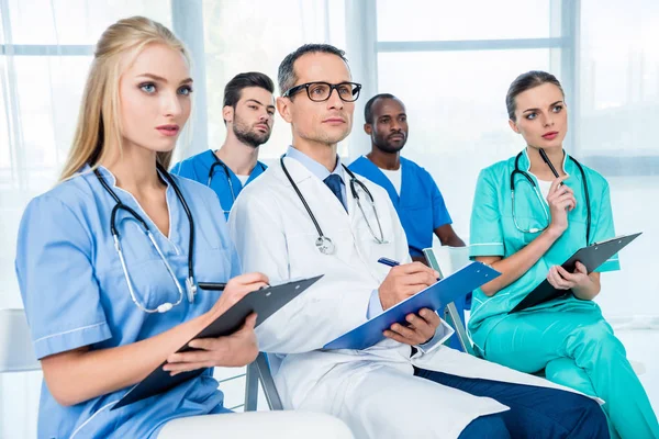 Médicos ouvindo palestra e escrita — Fotografia de Stock