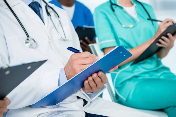 Doctors writing in clipboards — Stock Photo