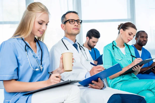 Doctors listening to lecture and writing — Stock Photo