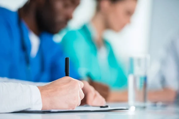 Infirmière écriture dans presse-papiers — Photo de stock