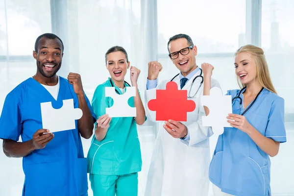 Médicos sosteniendo piezas del rompecabezas - foto de stock