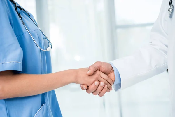 Medico e infermiere stringendo la mano — Foto stock