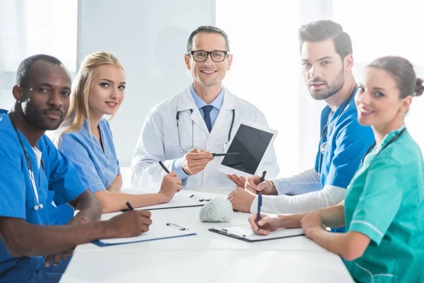 Médicos sentados en la mesa de conferencias - foto de stock