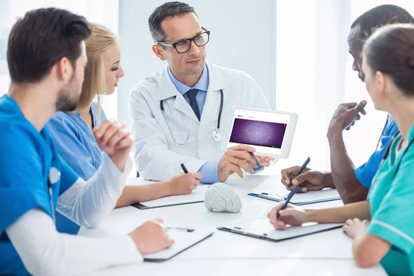 Ärzte unterhalten sich und schauen auf Tablet — Stockfoto