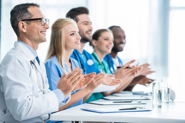 Doctors sitting at table and clapping — Stock Photo