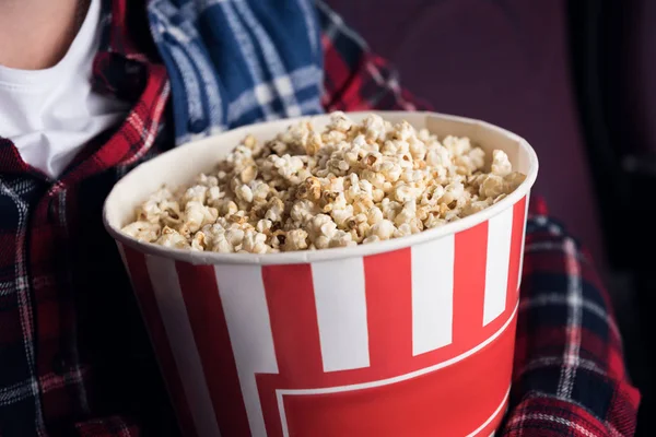 Cropped view of man holding big basket of popcorn in movie theater — Stock Photo