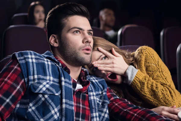 Joven pareja asustada con palomitas de maíz viendo película de terror en el cine - foto de stock