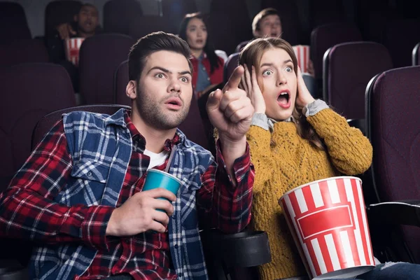 Young scared couple with popcorn watching movie in cinema — Stock Photo