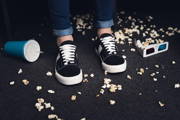 Sezione bassa di gambe femminili sul pavimento disordinato nel cinema — Foto stock