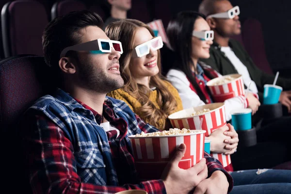 Young friends in 3d glasses with popcorn and soda watching movie in cinema — Stock Photo
