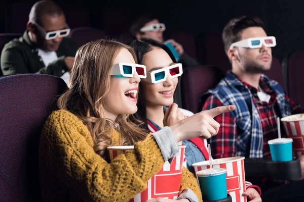 Jeunes amis souriants dans des lunettes 3D avec pop-corn regarder le film dans le cinéma — Photo de stock