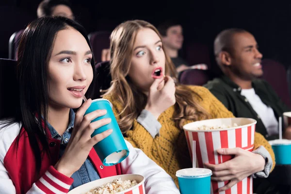 Young emotional friends with popcorn watching film in movie theater — Stock Photo