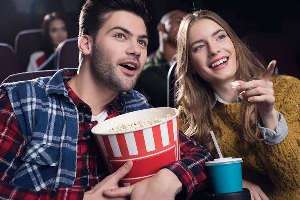 Young smiling couple with popcorn watching movie in cinema — Stock Photo