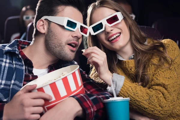 Jeune couple en 3d lunettes manger pop-corn tout en regardant un film au cinéma — Photo de stock