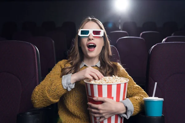 Jovem animado mulher em 3d óculos com grande cesta de pipoca assistindo filme no cinema — Fotografia de Stock