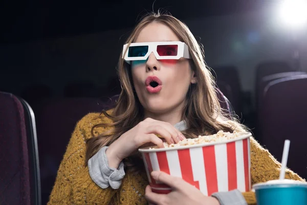 Mulher chocada em óculos 3d com grande cesta de pipoca assistindo filme no cinema — Fotografia de Stock