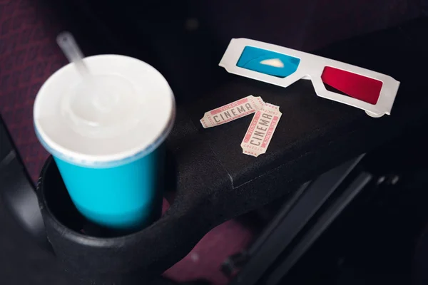 Tickets, 3d glasses and paper cup with soda on seat in movie theater — Stock Photo