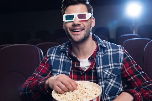 Homme souriant dans des lunettes 3D avec du pop-corn regarder un film au cinéma — Photo de stock