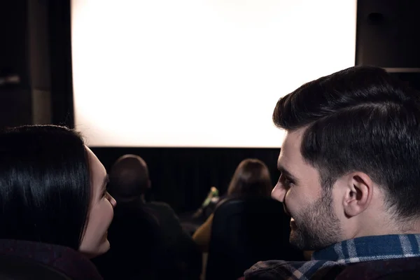 Rear view of friends sitting in cinema with white blank screen — Stock Photo